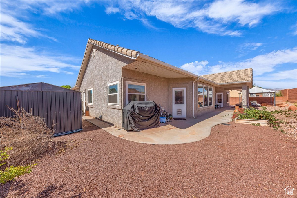 Rear view of house with a patio, stucco siding, and a tiled roof