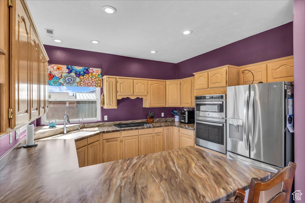 Kitchen with appliances with stainless steel finishes, recessed lighting, a peninsula, and light brown cabinets