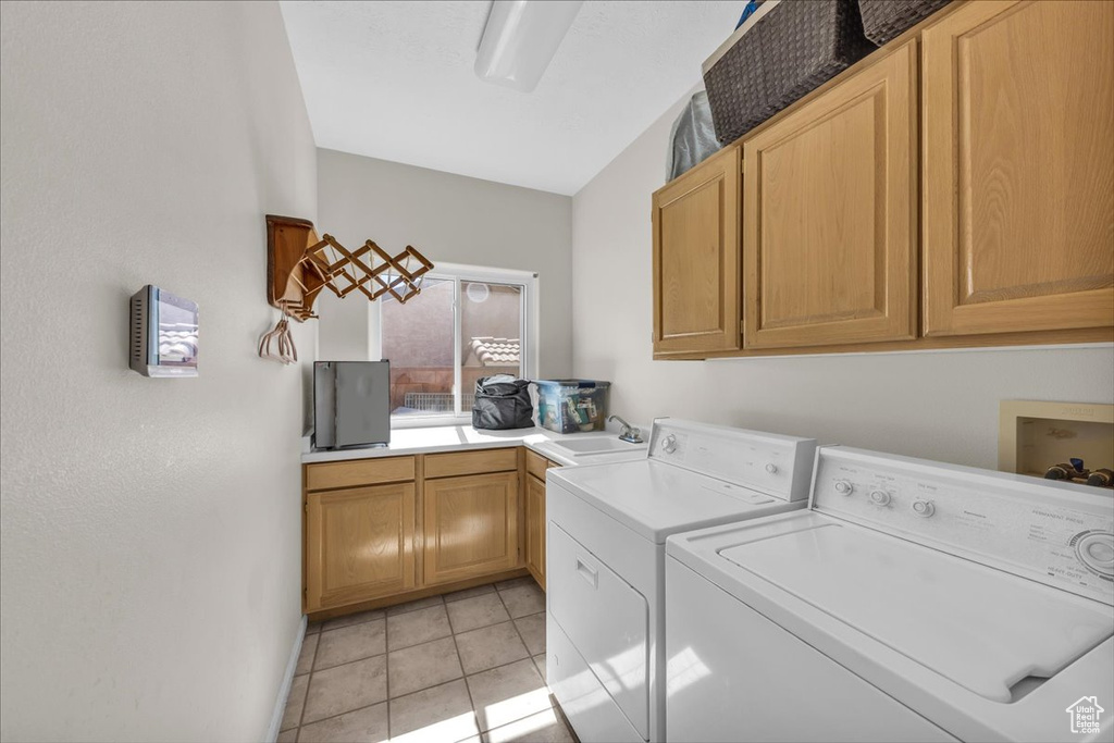 Laundry area featuring cabinet space, washer and clothes dryer, and light tile patterned floors
