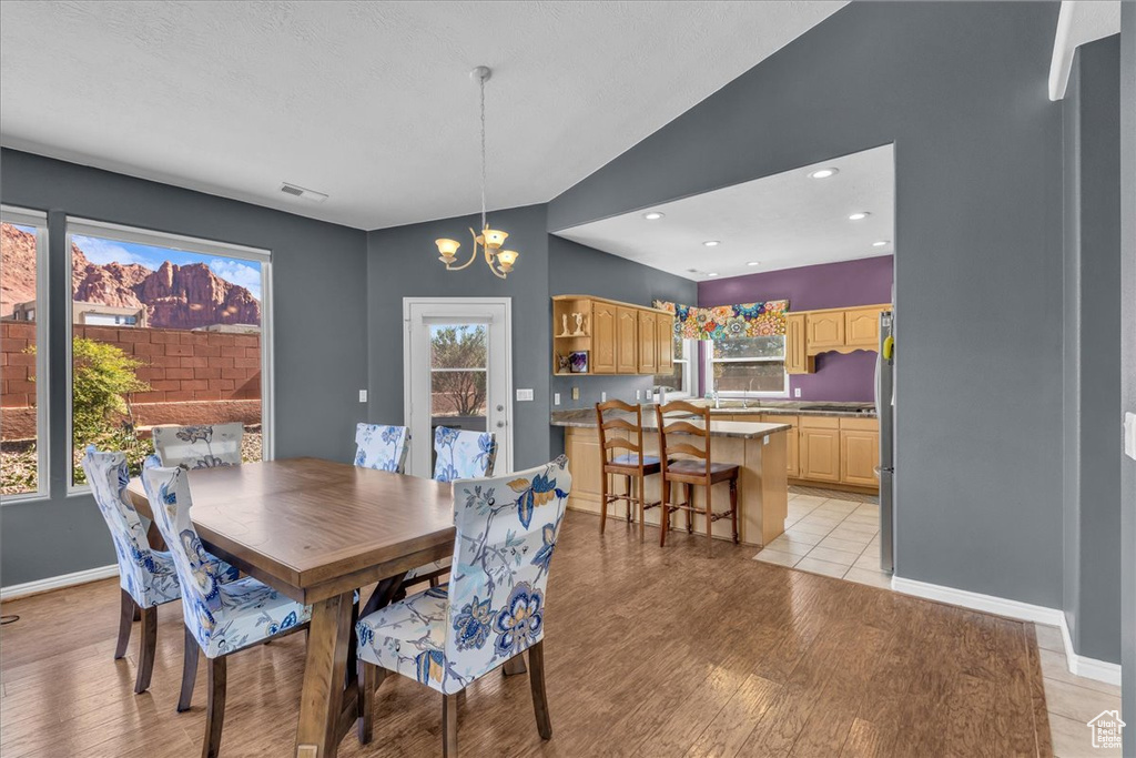 Dining area with a chandelier, light wood-style flooring, healthy amount of natural light, lofted ceiling, and recessed lighting