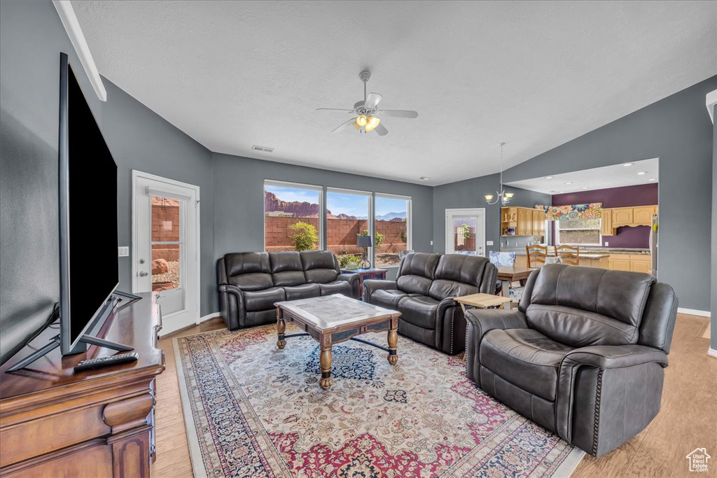 Living area with light wood-style floors, a ceiling fan, and vaulted ceiling