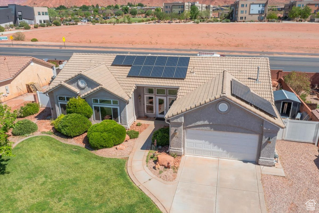View of front of property with a tiled roof, driveway, roof mounted solar panels, stucco siding, and a residential view