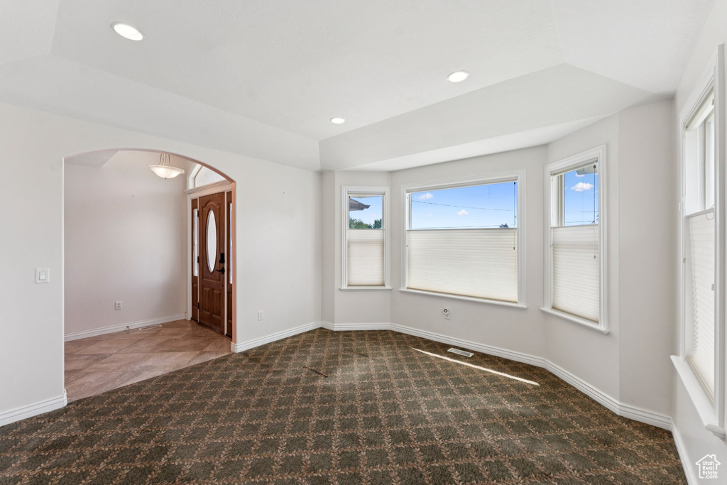 Carpeted empty room featuring arched walkways and recessed lighting