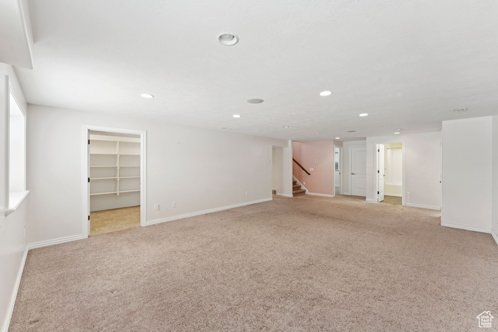 Basement featuring light colored carpet, recessed lighting, and stairs