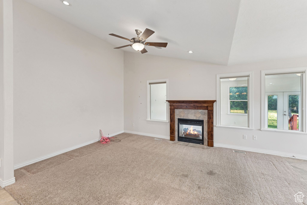 Unfurnished living room with lofted ceiling, carpet floors, a ceiling fan, a tiled fireplace, and recessed lighting