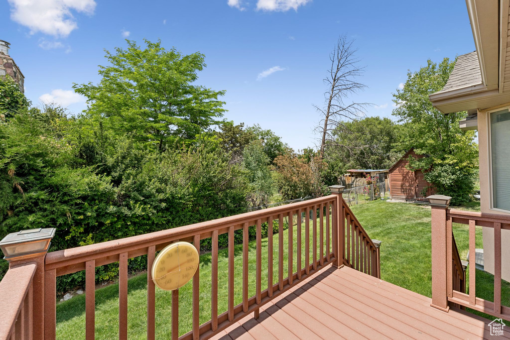 Wooden deck featuring a lawn and a storage shed