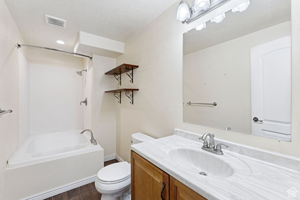 Full bath with shower / bath combination, vanity, and wood finished floors