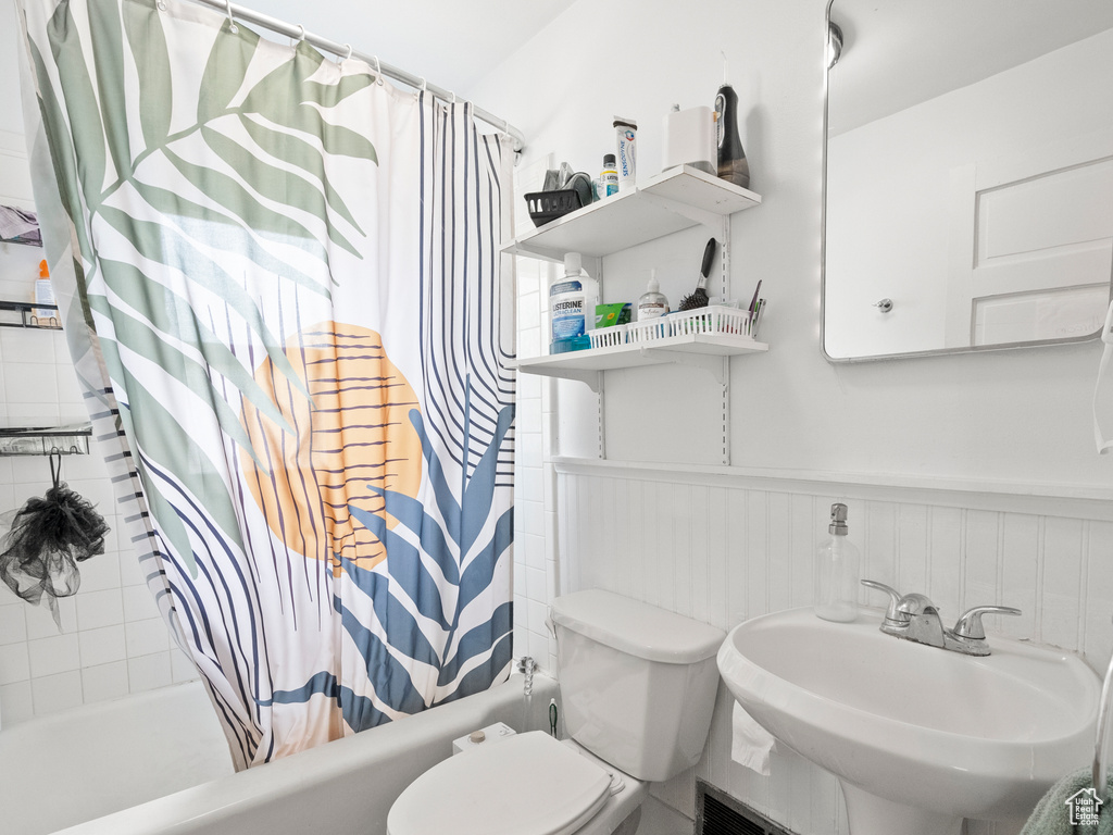Full bath with shower / tub combo and a wainscoted wall