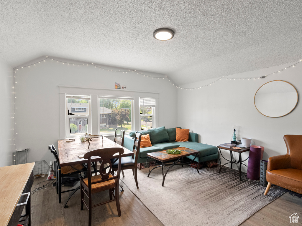 Dining space featuring a textured ceiling, light wood-style floors, and vaulted ceiling