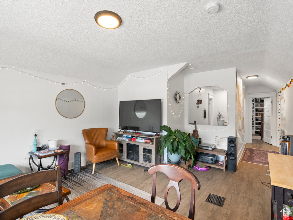Living area with a textured ceiling, wood finished floors, and lofted ceiling