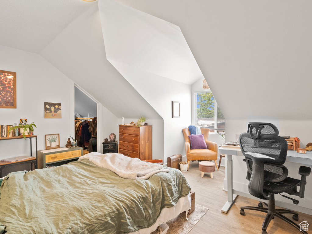 Bedroom with light wood finished floors, lofted ceiling, a desk, a spacious closet, and a closet