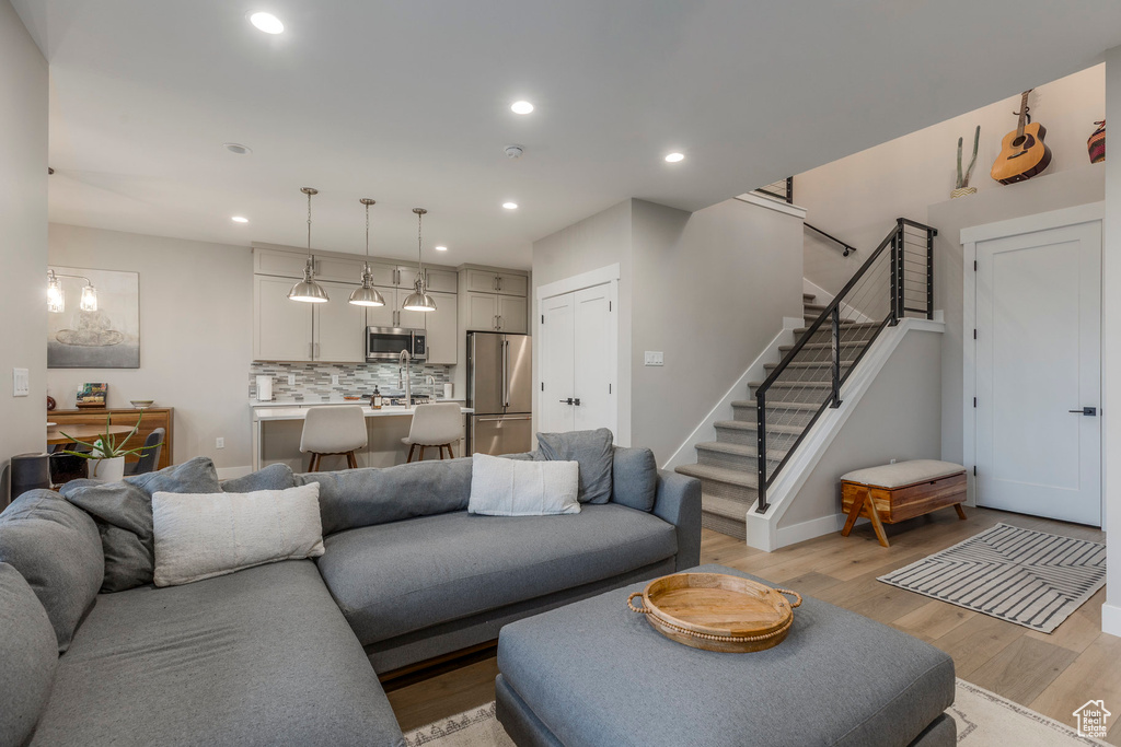 Living area with light wood-style floors, stairs, and recessed lighting