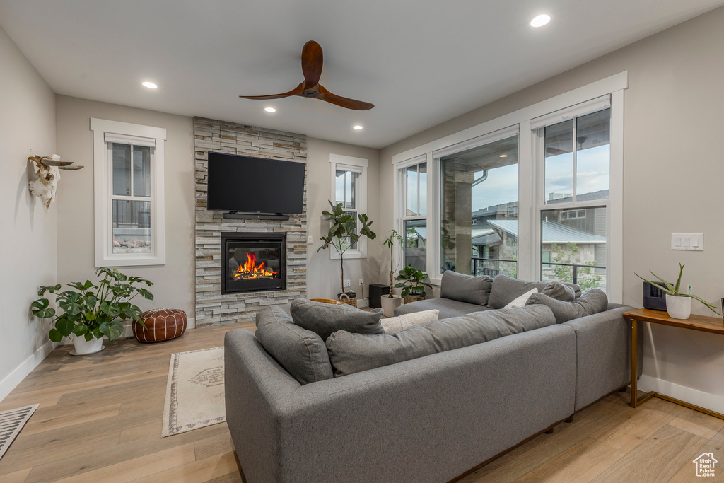 Living room featuring a ceiling fan, a fireplace, light wood-type flooring, and recessed lighting