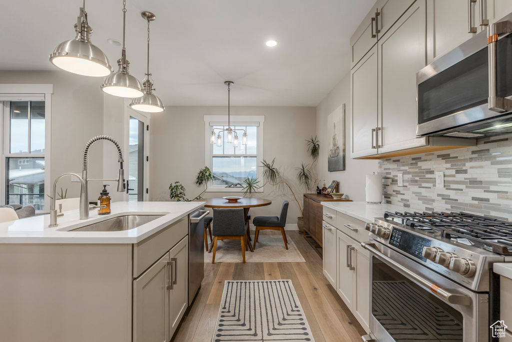 Kitchen featuring stainless steel appliances, light wood-style floors, tasteful backsplash, light countertops, and recessed lighting