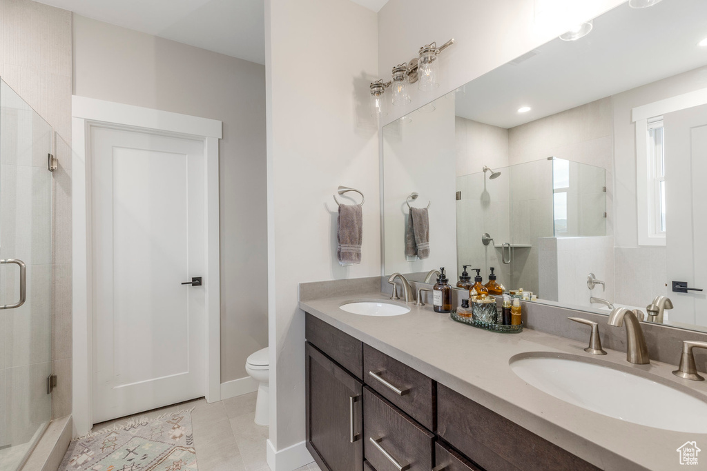 Bathroom with a stall shower, double vanity, and tile patterned flooring