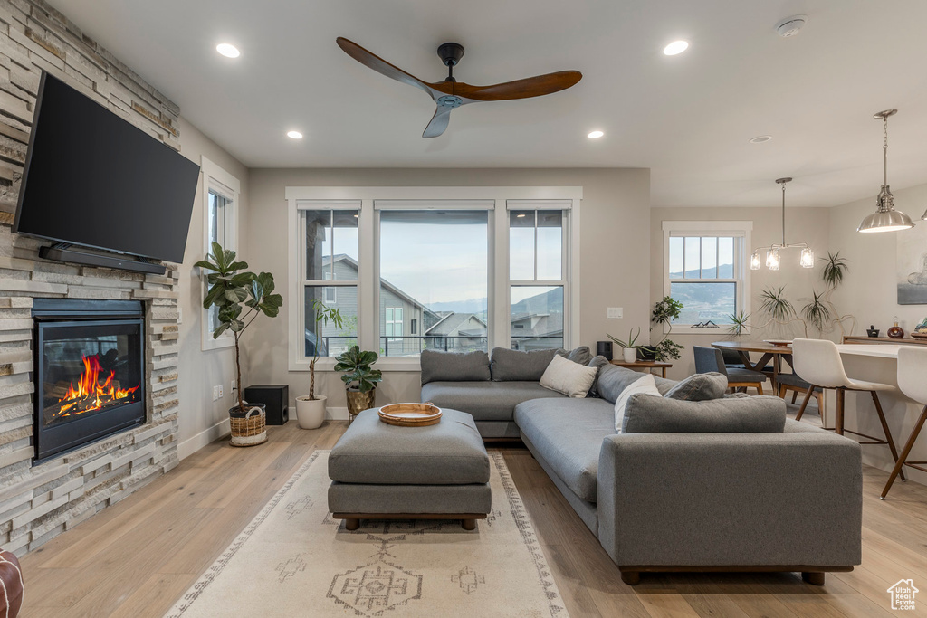 Living room with ceiling fan, light wood-style flooring, a fireplace, and recessed lighting