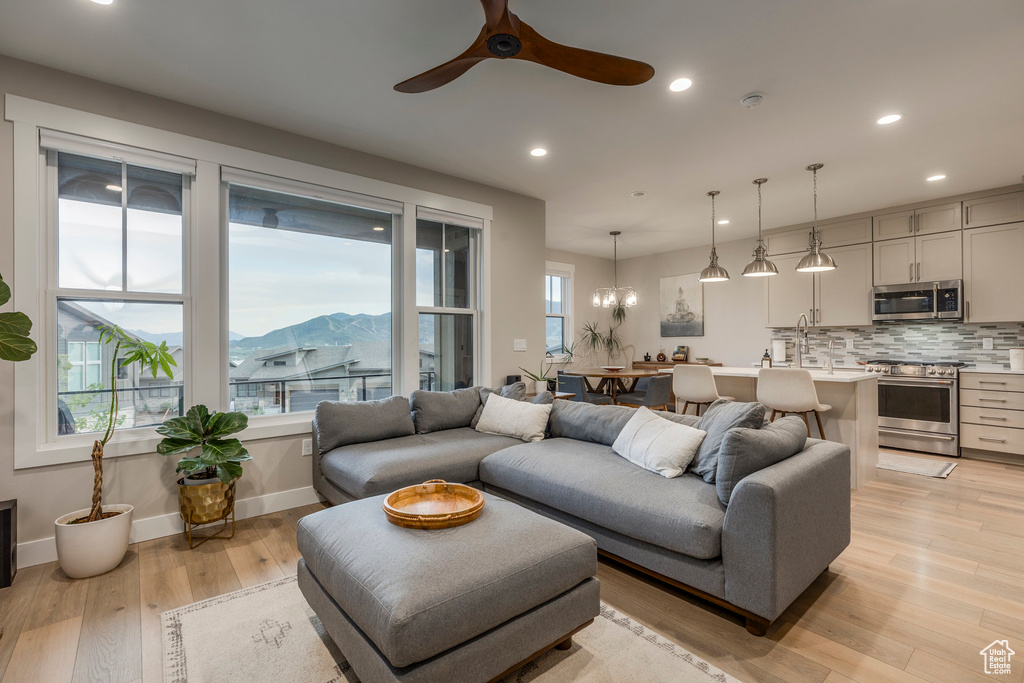 Living room with light wood-type flooring, recessed lighting, ceiling fan, a mountain view, and a chandelier