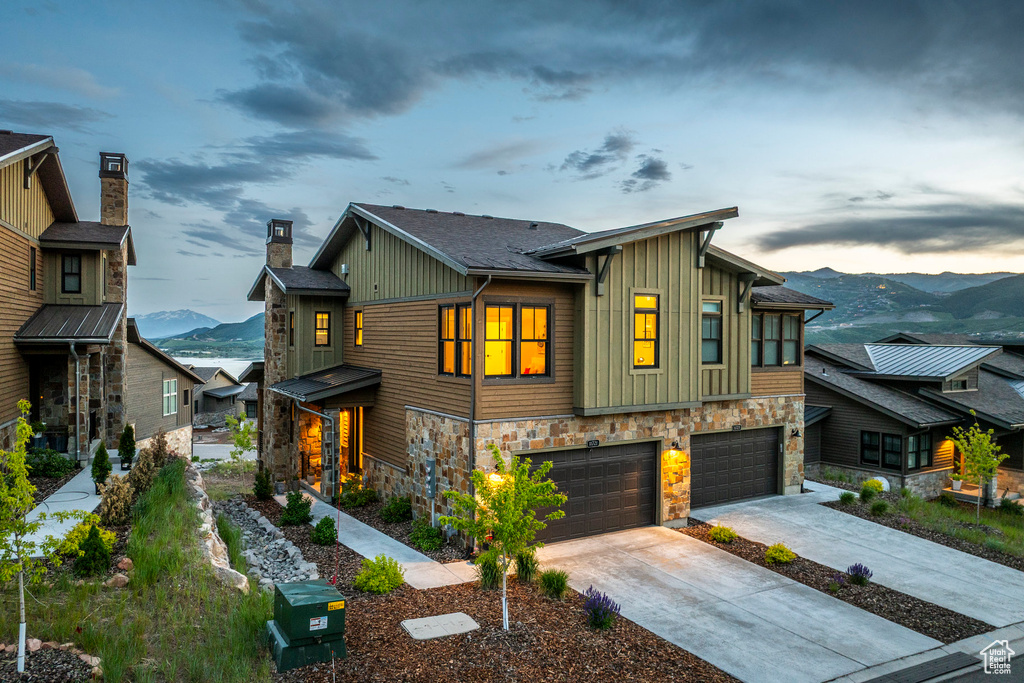 View of front facade with a mountain view, board and batten siding, stone siding, an attached garage, and concrete driveway