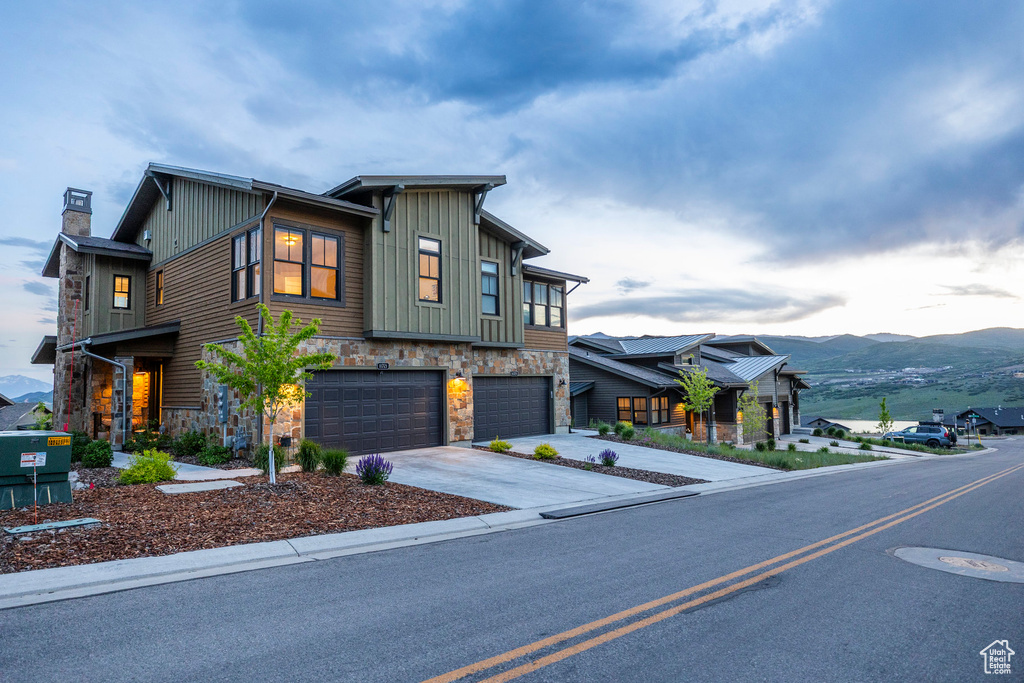 Modern home featuring a garage, board and batten siding, stone siding, and driveway