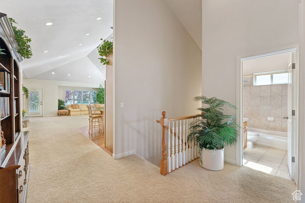 Hall with carpet, an upstairs landing, recessed lighting, tile patterned floors, and high vaulted ceiling