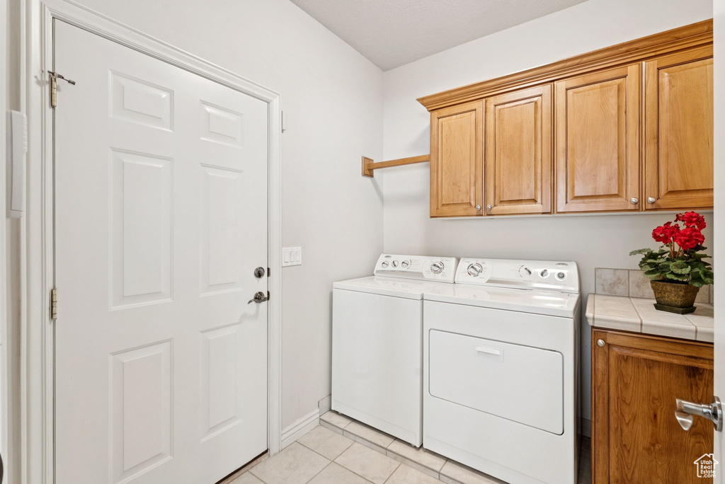 Laundry room featuring cabinet space, washing machine and dryer, and light tile patterned floors