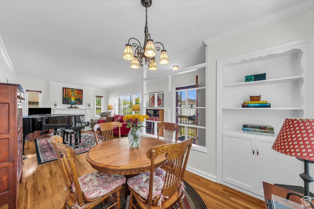 Dining room with light wood-style flooring, crown molding, and a chandelier