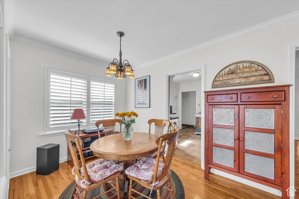 Dining room with a chandelier, ornamental molding, and light wood finished floors