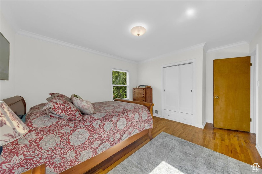 Bedroom featuring ornamental molding, wood finished floors, and a closet