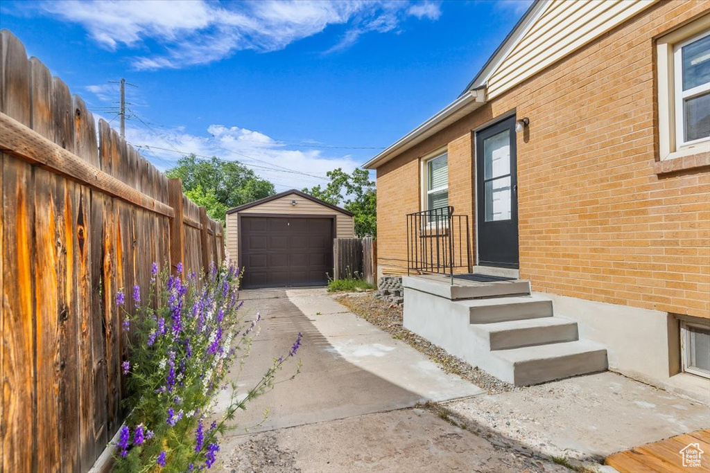 Doorway to property featuring brick siding, a garage, and concrete driveway