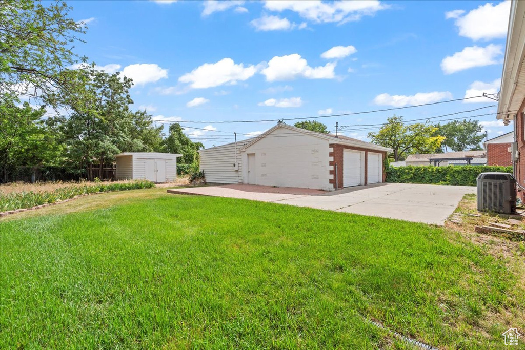 View of grassy yard with an outbuilding and a detached garage