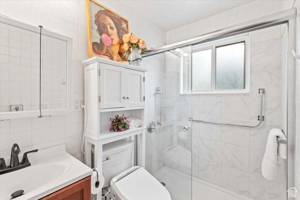 Full bathroom with vanity, a shower stall, backsplash, and tile walls