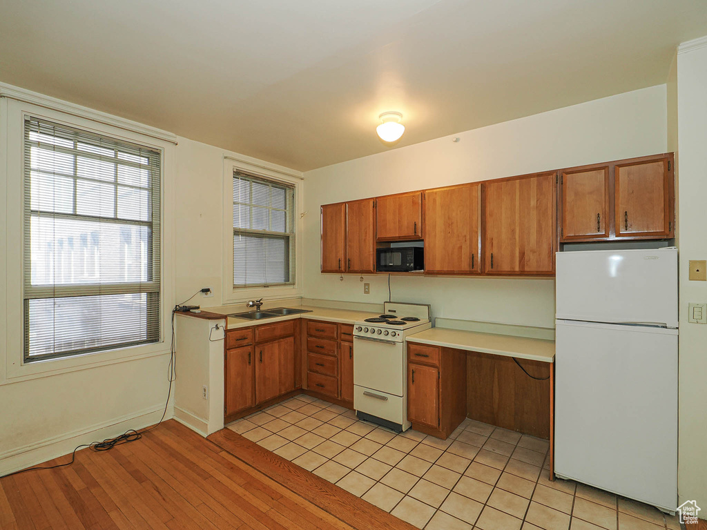 Kitchen featuring white appliances, light countertops, brown cabinetry, and light wood-type flooring