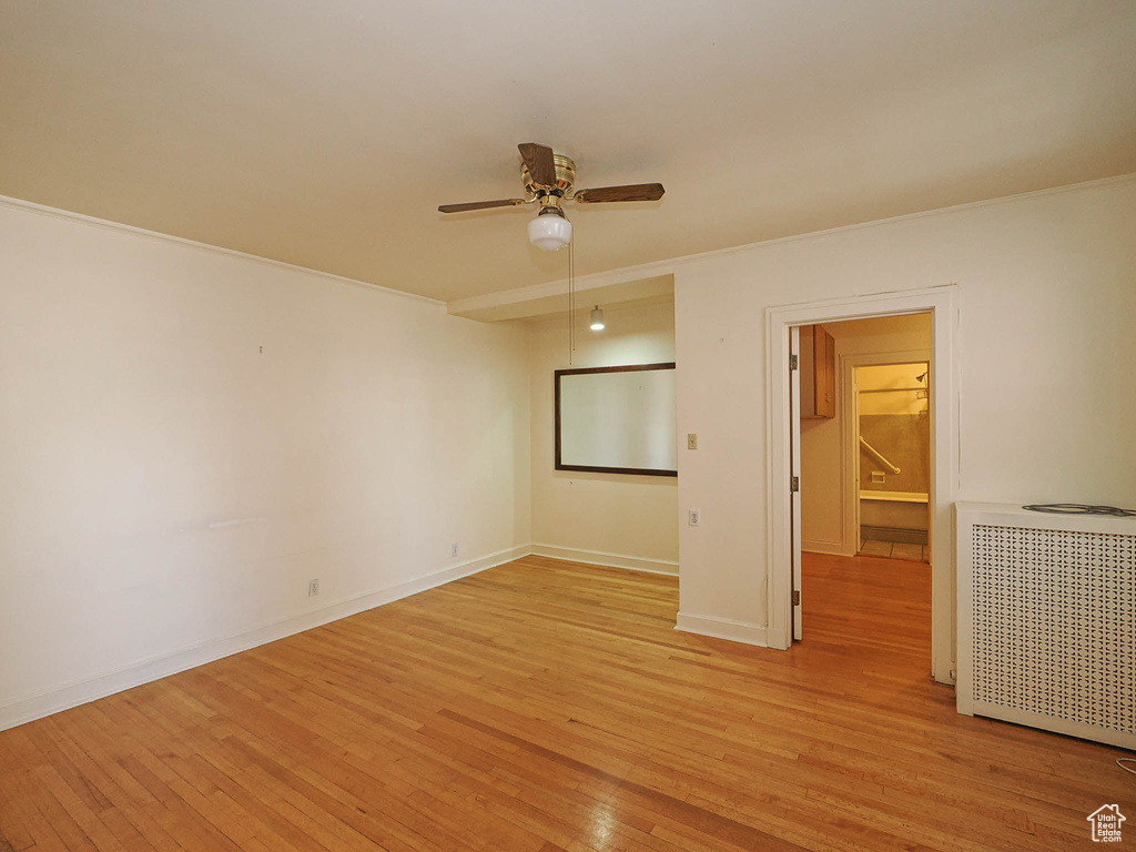 Spare room with ceiling fan, ornamental molding, light wood-style floors, and radiator
