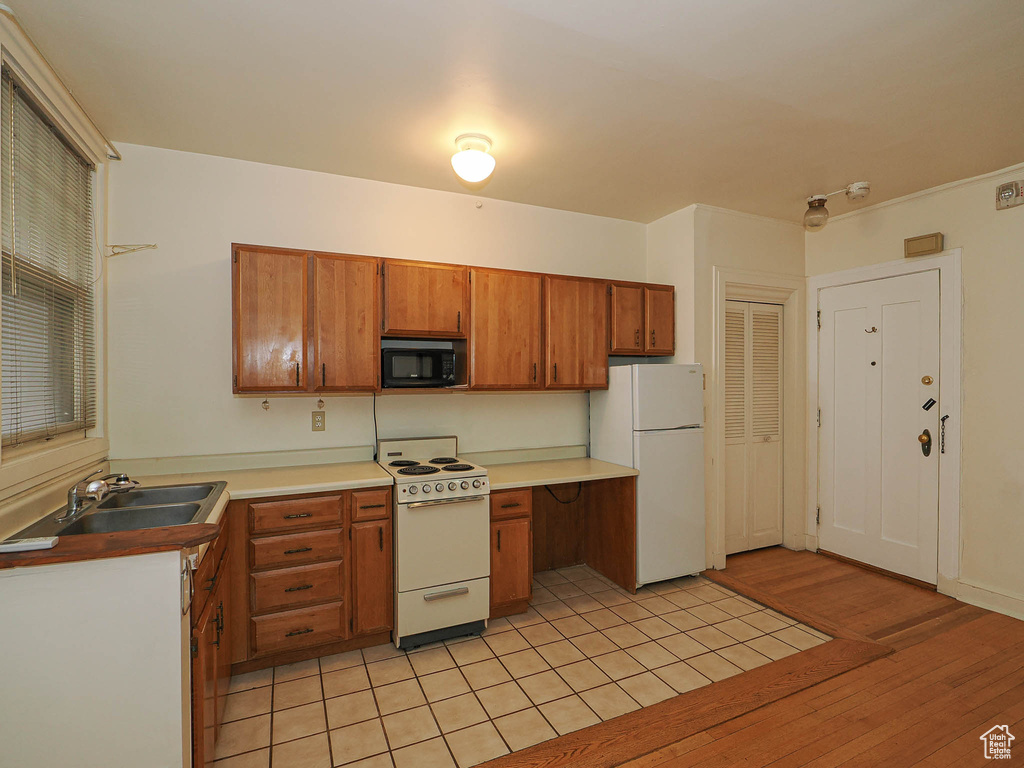 Kitchen featuring white appliances, brown cabinetry, light wood finished floors, and light countertops