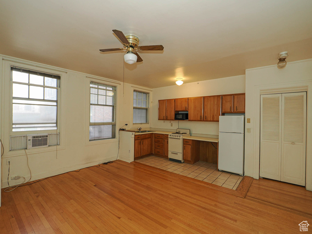 Kitchen with white appliances, light wood-style floors, brown cabinets, light countertops, and a ceiling fan