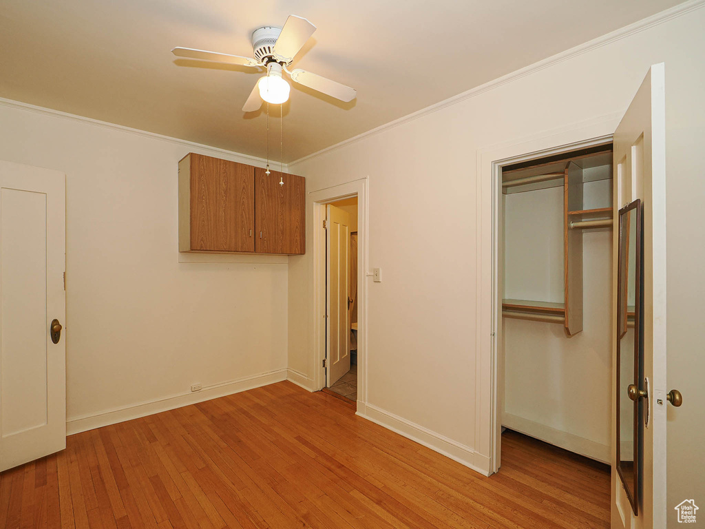 Unfurnished bedroom with light wood-style flooring, ornamental molding, a closet, and a ceiling fan