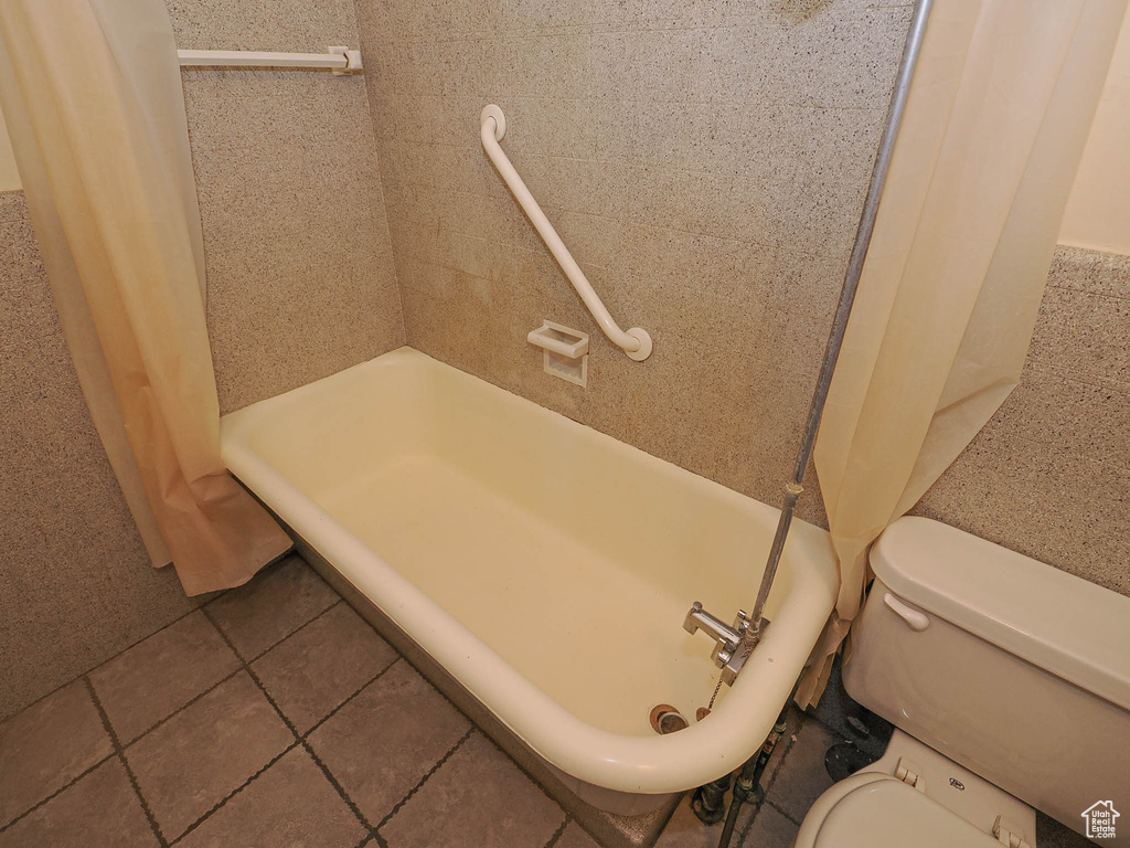 Bathroom with a shower with curtain and tile patterned floors