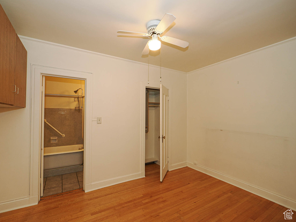 Unfurnished bedroom with light wood-type flooring, crown molding, ensuite bath, a closet, and a ceiling fan