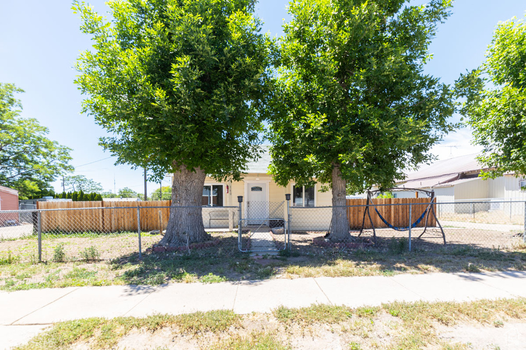 Obstructed view of property with a fenced front yard and a gate