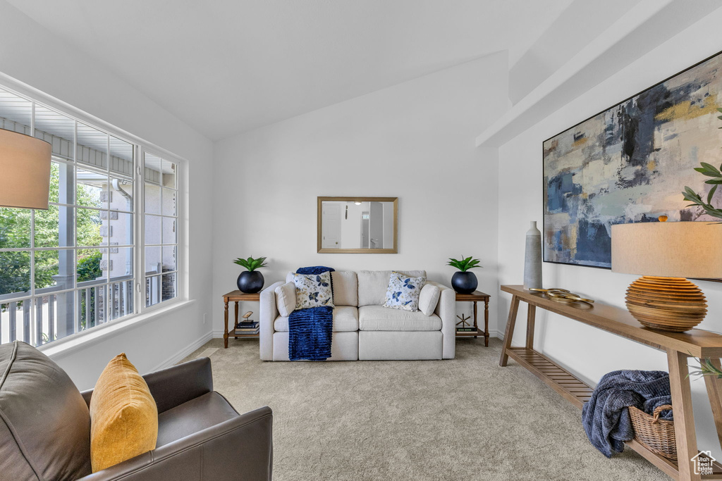 Carpeted living area with baseboards and vaulted ceiling