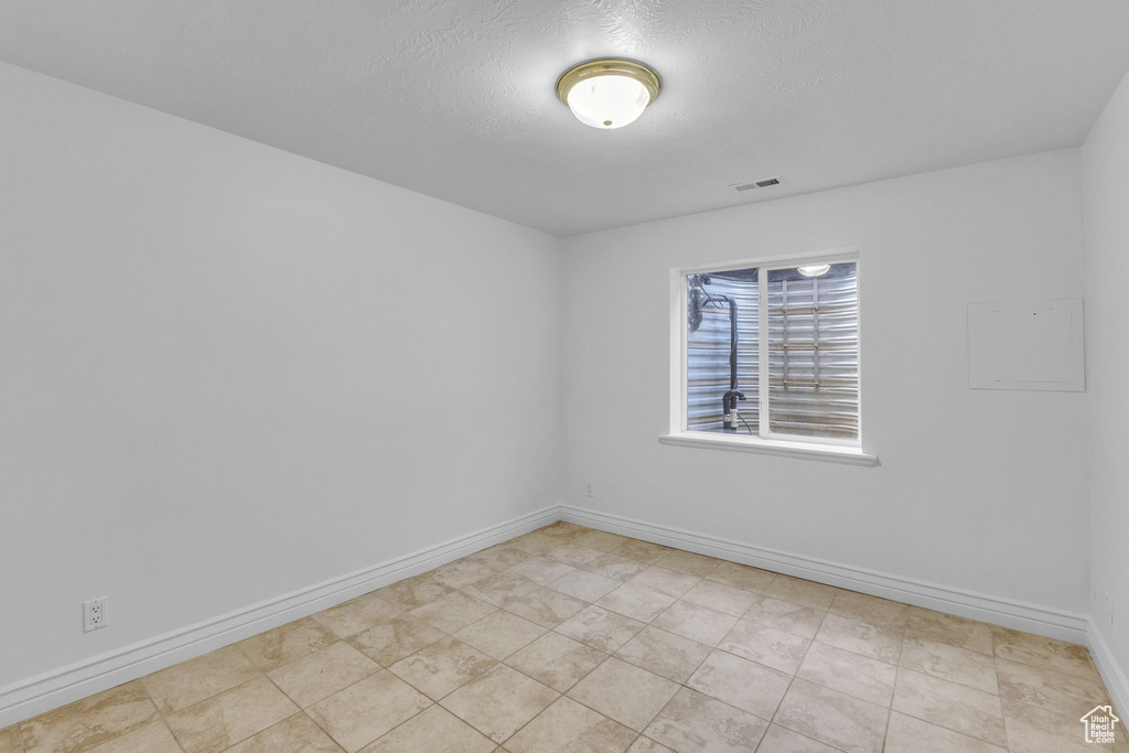 Spare room with baseboards and a textured ceiling
