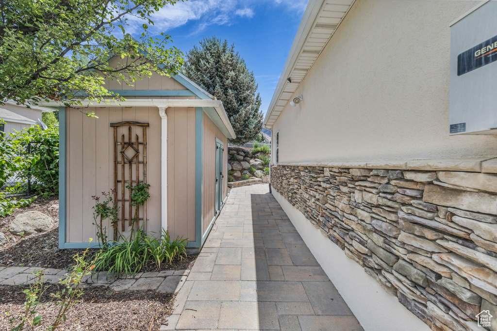 View of side of home with a storage unit and stone siding