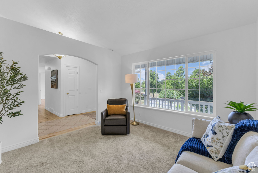 Tiled living area featuring arched walkways and carpet floors