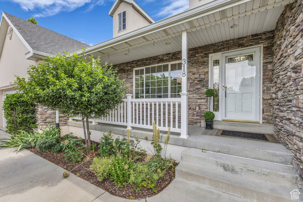Property entrance with stone siding, covered porch, and stucco siding
