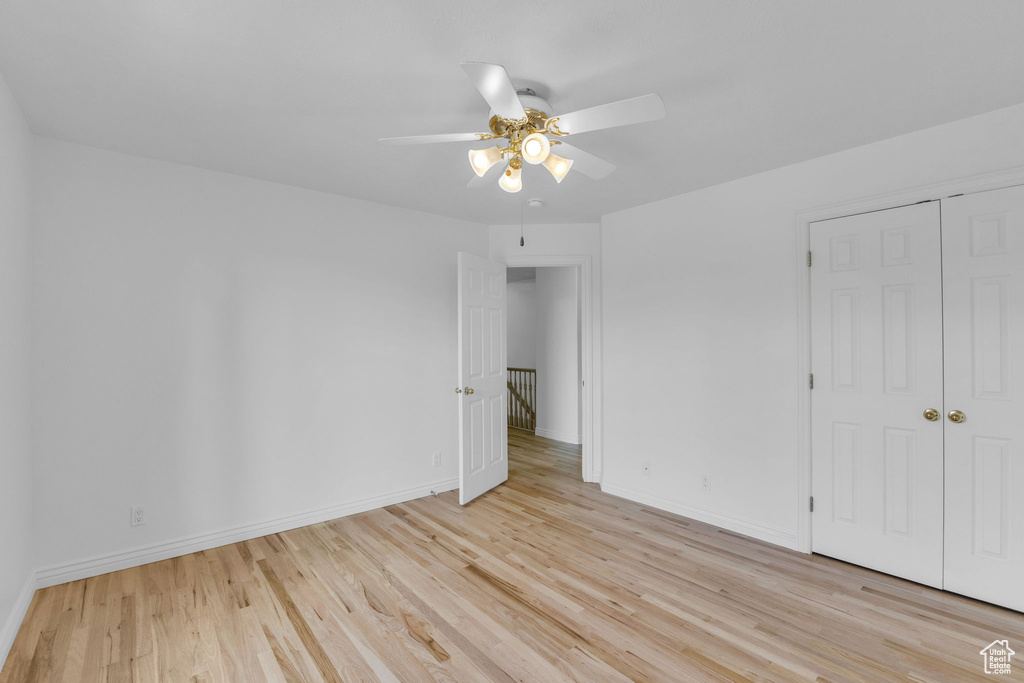 Unfurnished bedroom with light wood-type flooring, ceiling fan, and a closet