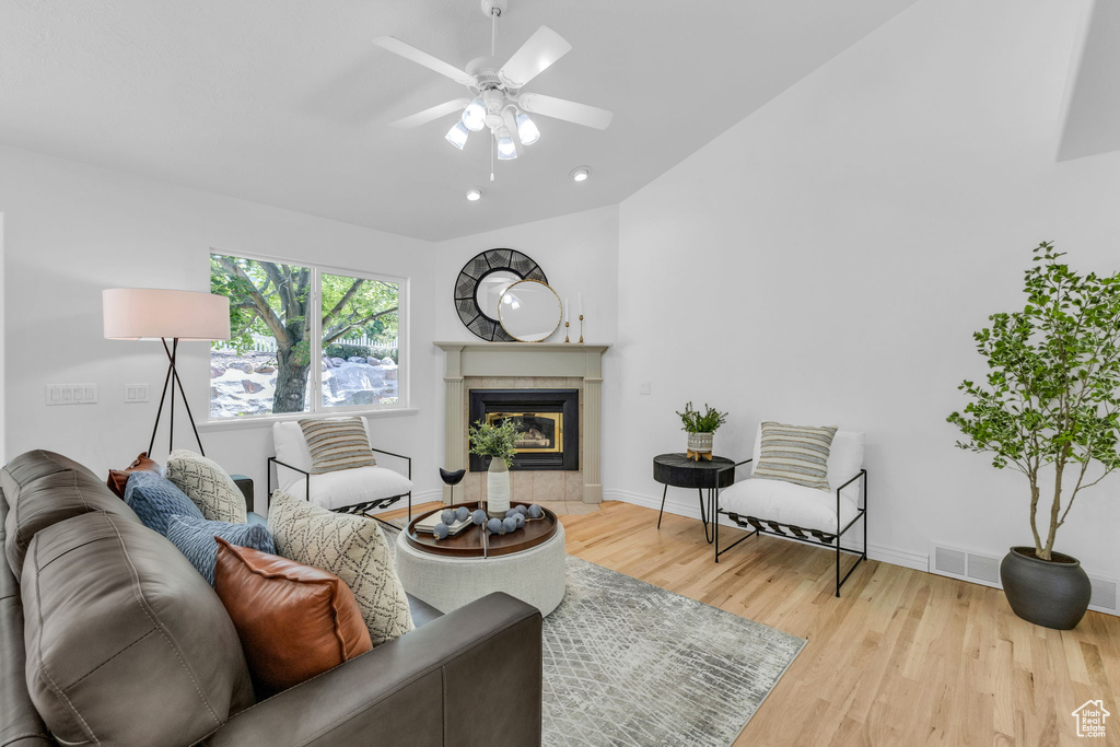 Living area with wood finished floors, a ceiling fan, a tile fireplace, recessed lighting, and lofted ceiling