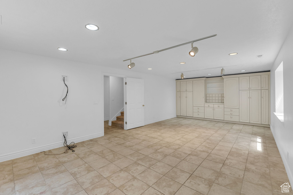Unfurnished room with recessed lighting, rail lighting, and stairs
