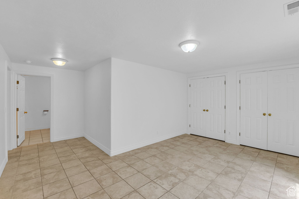 Unfurnished bedroom featuring two closets and light tile patterned floors