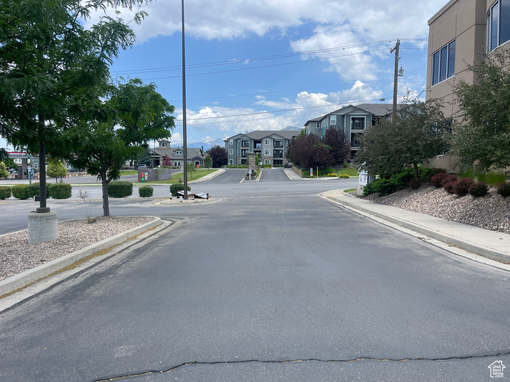 View of asphalt road with curbs, a residential view, and sidewalks