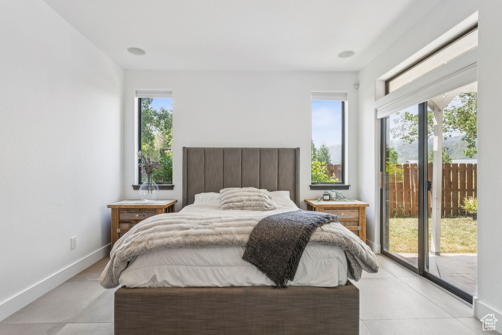 Bedroom with access to exterior, multiple windows, and light tile patterned floors